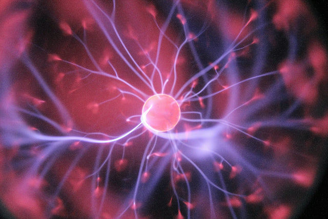 A plasma ball with pink and purple filaments of light branching out from its center